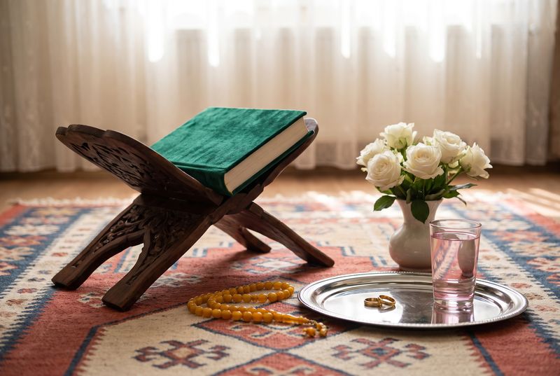 A carved wooden book stand, prayer beads, rings on a silver tray and white roses for a religious nikâh