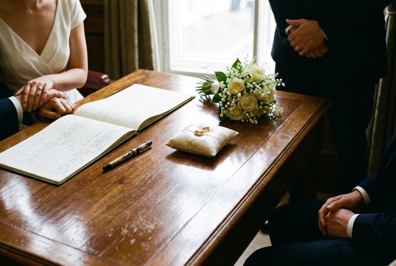 A register office signing table with the marriage register, a pen and two rings