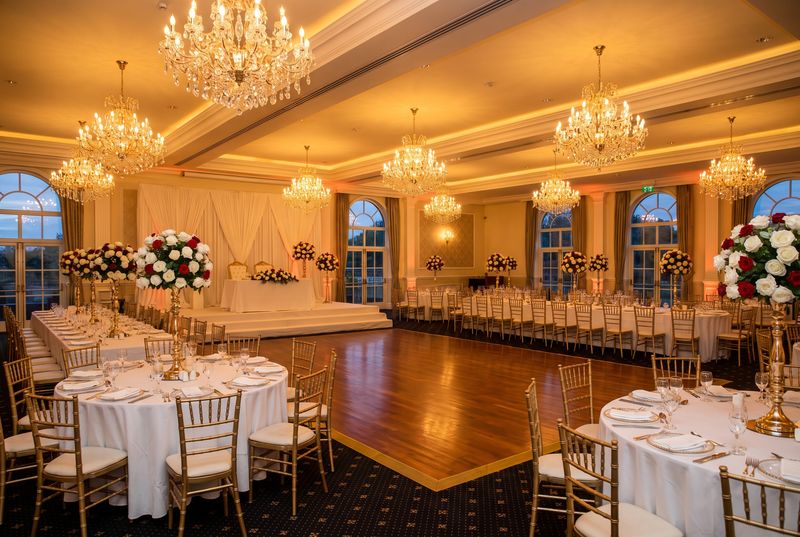 A grand Turkish wedding hall set with round tables, gold chairs, chandeliers and a dance floor
